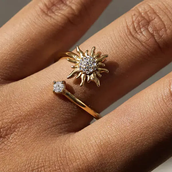 Gold sun-shaped ring with diamond accents on a finger