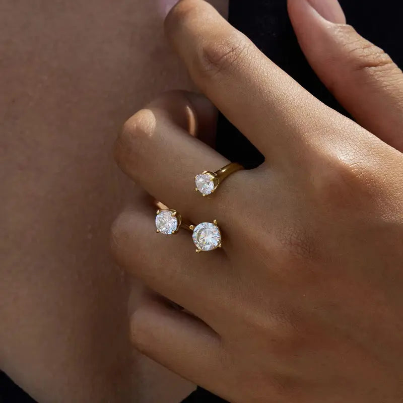 Close-up of a hand wearing two gold rings with diamond-like stones.